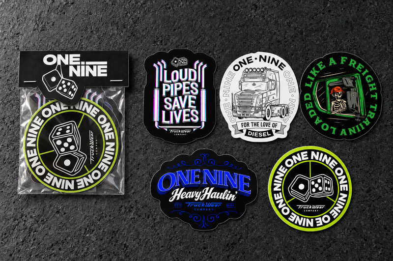 One Nine Budget sticker pack beside its five individual die cut sticker designs on a charcoal studio surface.