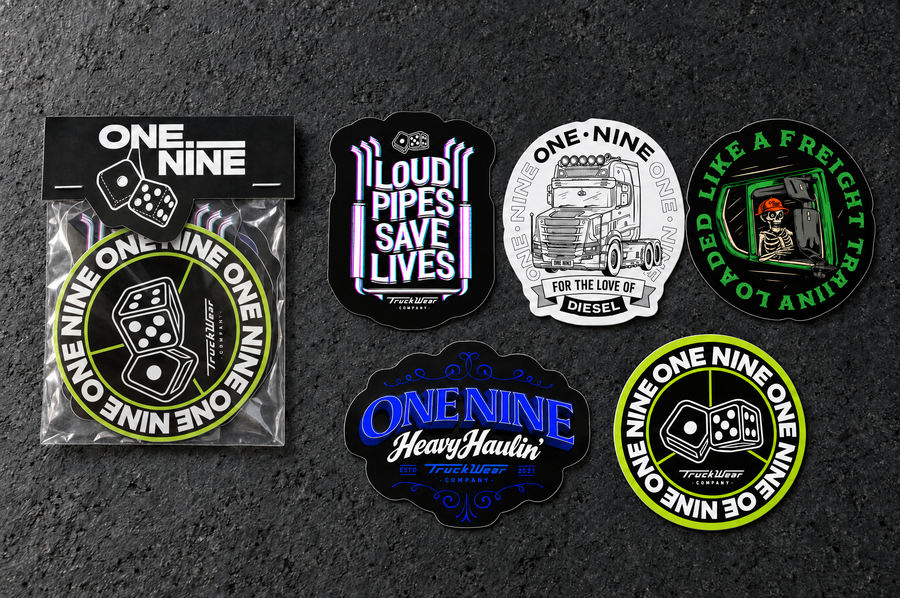 One Nine Budget sticker pack beside its five individual die cut sticker designs on a charcoal studio surface.