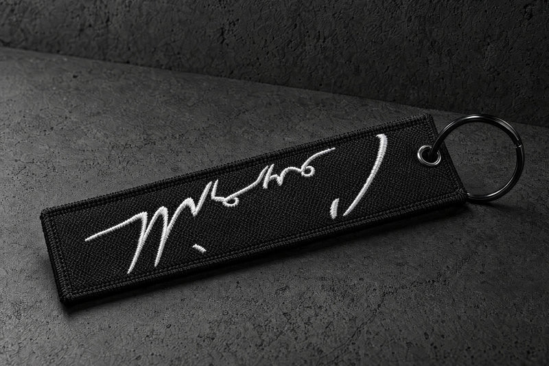 embroidered keyrings on a charcoal studio surface — Projectprint