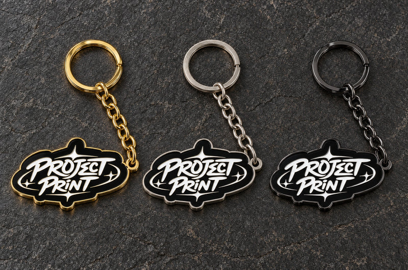 Project Print custom metal enamel keyring design in shiny gold / matt nickel / black nickel, showing three finish options.
