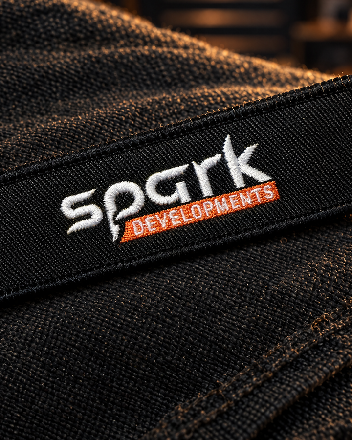 Spark Developments embroidered fabric keyring in black with white and orange stitching — Project Print customer work, view 2