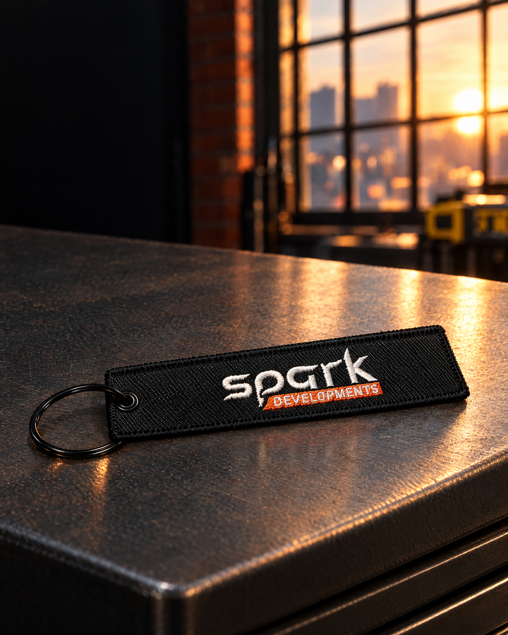 Spark Developments embroidered fabric keyring in black with white and orange stitching — Project Print customer work, view 3