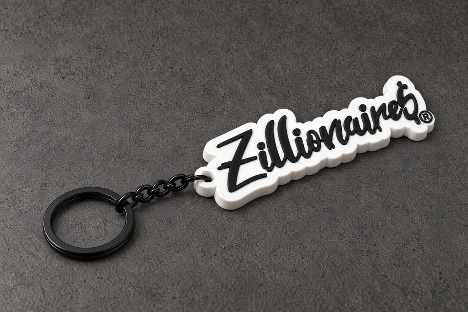 zillionaire white script keyring on a charcoal studio surface — Projectprint